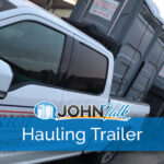 A closeup of a pickup pulling a hauling trailer with gray portable toilets