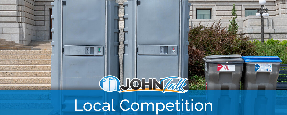 Two portable restrooms and two garbage cans in front of a building