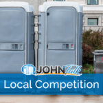 Two portable restrooms and two garbage cans in front of a building