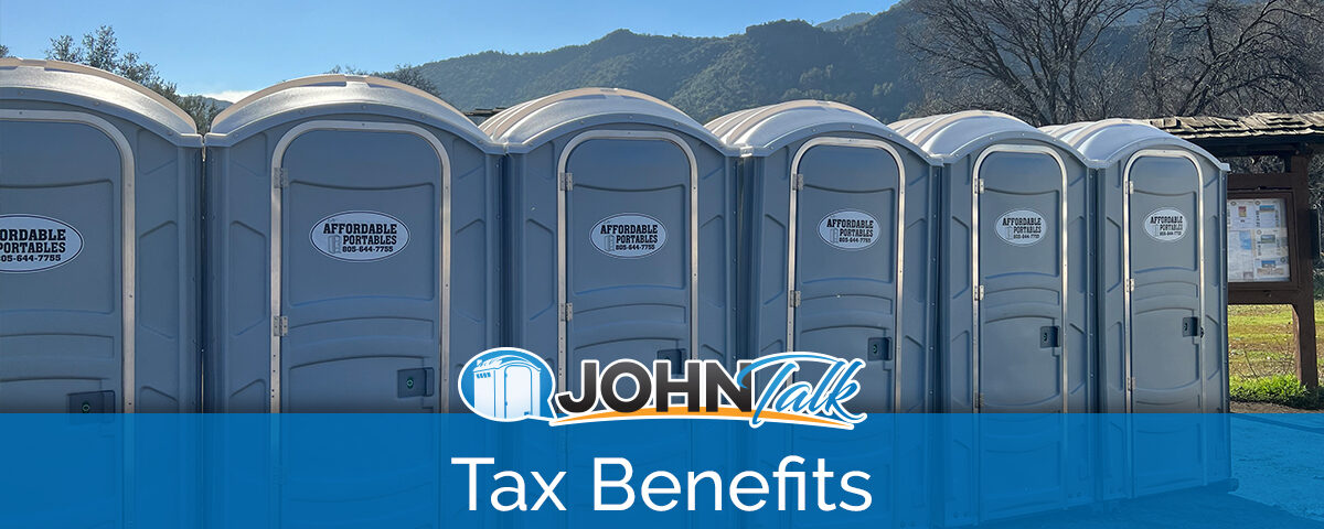 A row of gray portable toilets with mountains in the background