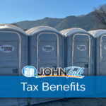 A row of gray portable toilets with mountains in the background