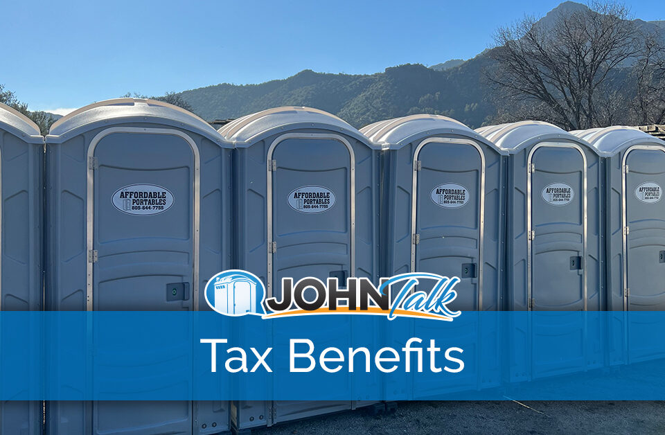 A row of gray portable toilets with mountains in the background