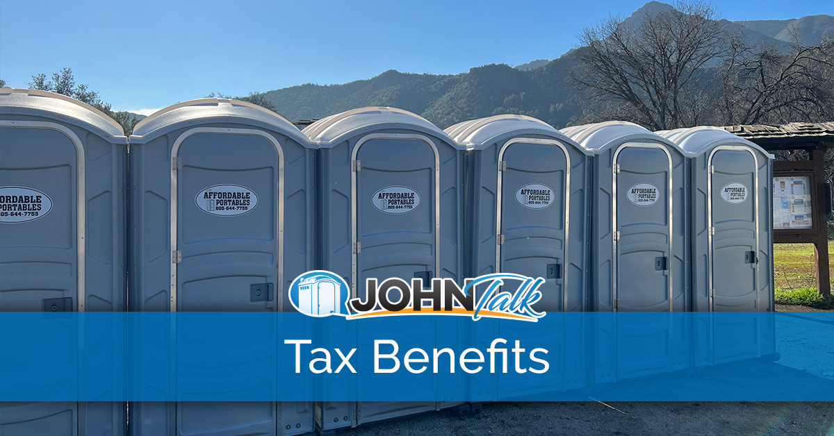 A row of gray portable toilets with mountains in the background