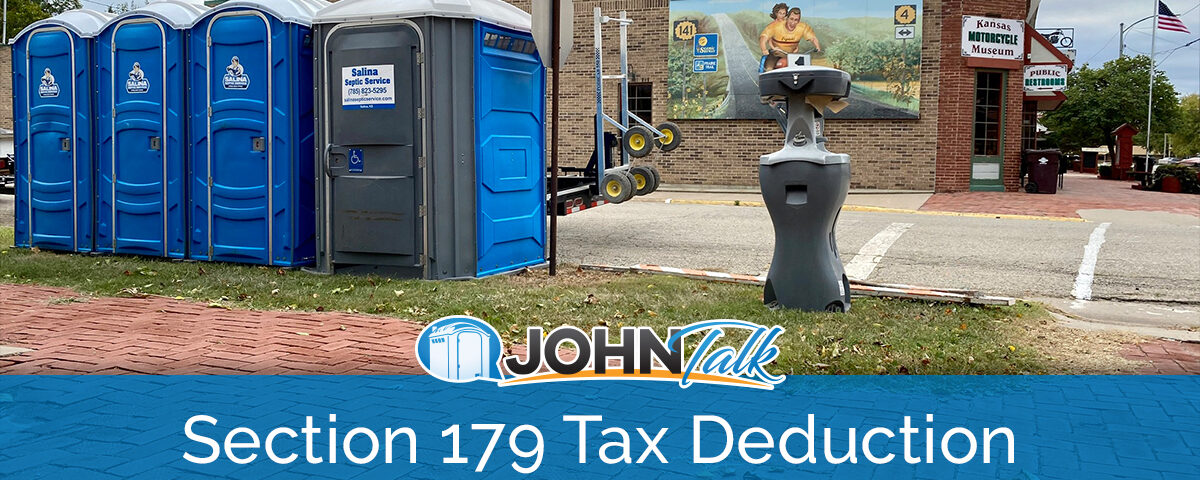 A row of blue portable toilets and a portable sink by the street with a building with a mural on it in the background