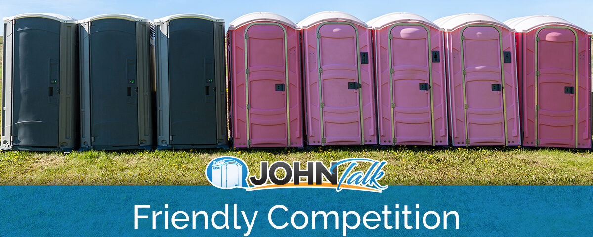 Gray portable toilets and pink portable toilets in a row in the grass